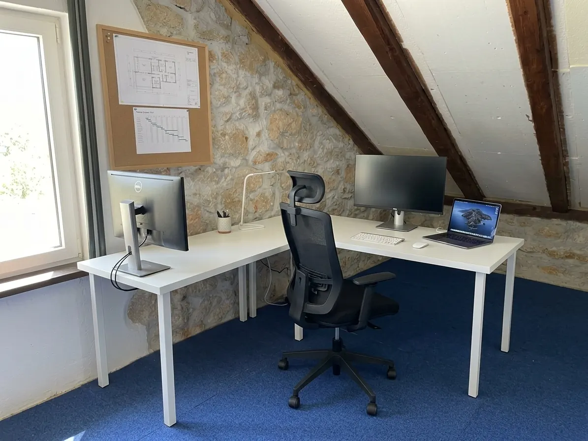 Attic workspace with two desks, external monitors and ergonomic office chairs