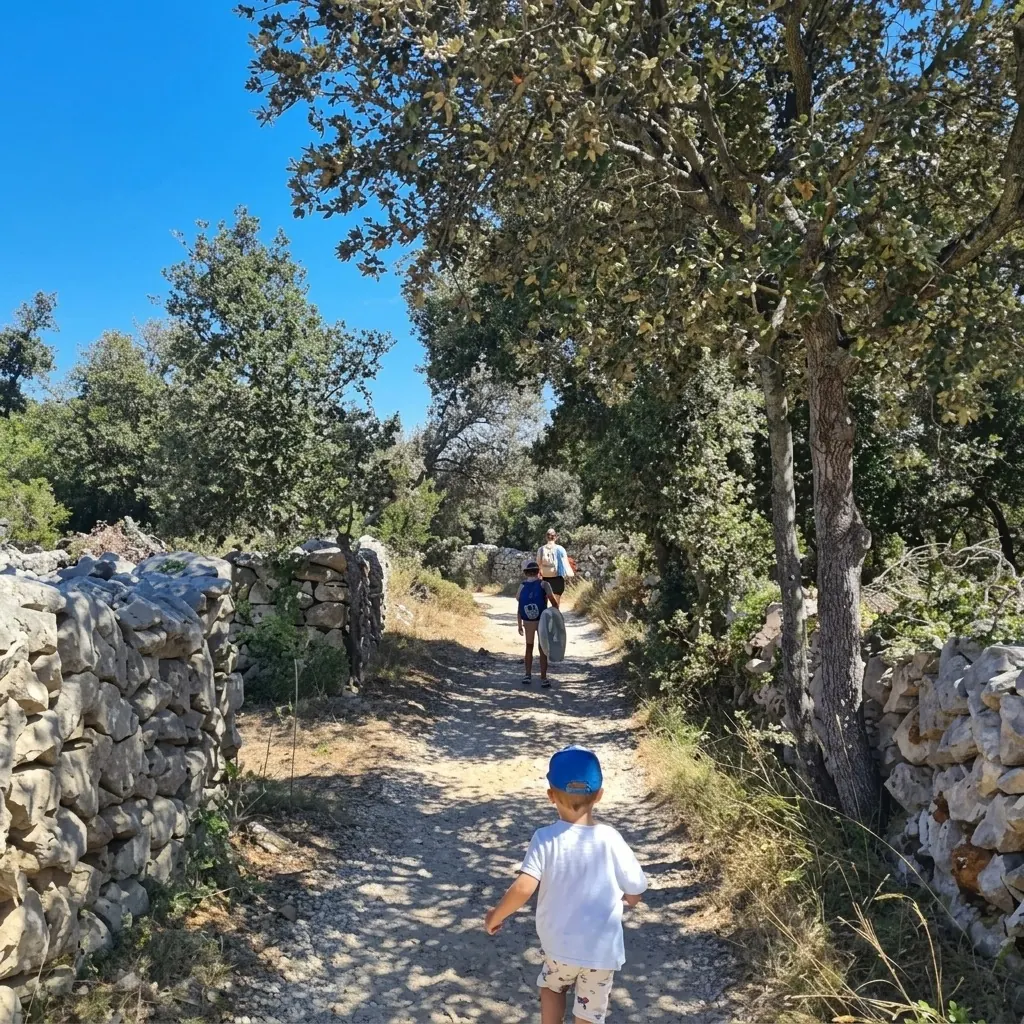A family with small children walking along a sunny path between dry-stone walls on Olib
